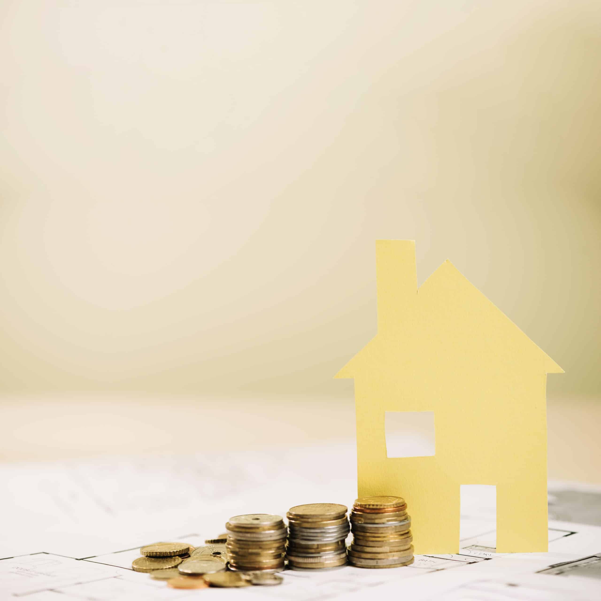 assurance emprunteur illustrée par une maison jaune et pièces de monnaie